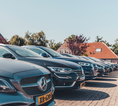 Geparkeerde personenauto’s op het terrein van Greven Automotive Rij personenauto’s die schuin naast elkaar geparkeerd staan op een buitenterrein, met huizen en bomen op de achtergrond.